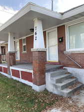 Doorway to property with brick siding and a porch