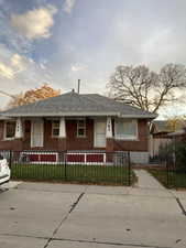 Ranch-style house with a fenced front yard, brick siding, a shingled roof, and covered porch