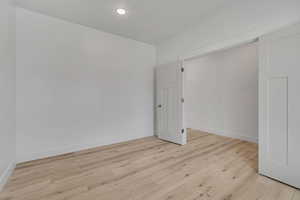 Spare room featuring light wood-style flooring and baseboards