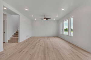 Unfurnished living room featuring recessed lighting, light wood-style floors, stairs, and a ceiling fan