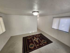 Carpeted empty room with a textured ceiling and baseboards