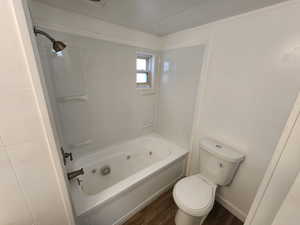 Bathroom featuring dark wood-type flooring and a combined bath / shower with jetted tub