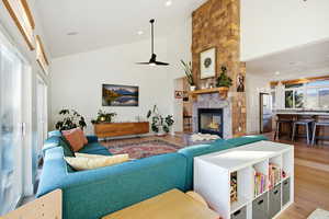 Living room with high vaulted ceiling, a fireplace, wood finished floors, ceiling fan, and recessed lighting