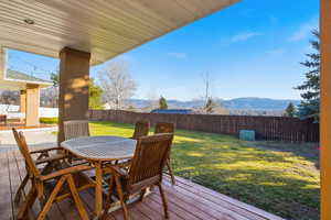 Wooden deck featuring outdoor dining area, a mountain view, and a fenced backyard