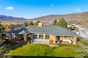 Rear view of property with a chimney, a patio, a shingled roof, and a mountain view