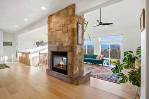 Living room with a multi sided fireplace, hardwood / wood-style flooring, a ceiling fan, and recessed lighting