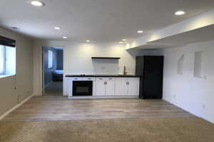 Bar area with black appliances, dark countertops, white cabinets, recessed lighting, and light wood-style flooring