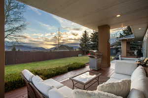 Fenced backyard with outdoor lounge area, area for grilling, and a deck with mountain view
