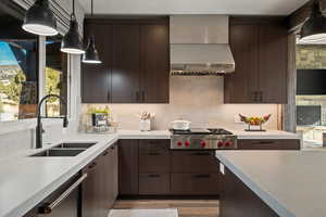 Kitchen with decorative light fixtures, wall chimney exhaust hood, stainless steel appliances, and decorative backsplash