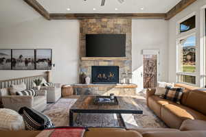Living area featuring beam ceiling, a fireplace, ceiling fan, and high vaulted ceiling
