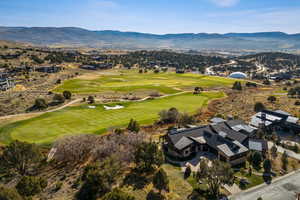Aerial view of property and surrounding area with mountains and a golf course