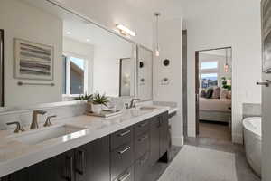 Ensuite bathroom with a freestanding bath, double vanity, backsplash, and light wood-type flooring