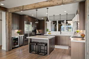 Kitchen with a breakfast bar area, pendant lighting, light countertops, recessed lighting, and beam ceiling