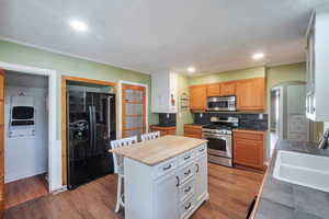 Kitchen featuring appliances with stainless steel finishes, a breakfast bar area, arched walkways, recessed lighting, and light wood-style floors