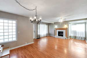 living room featuring plenty of natural light, light wood-style flooring, a ceiling fan, and a chandelier