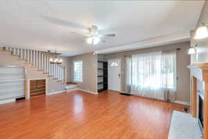 living room with a ceiling fan, a fireplace with flush hearth, light wood-style flooring