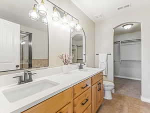 Master Suite full bathroom with a walk in closet, double vanity, and light colored carpet
