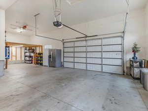 Garage featuring stainless steel refrigerator with ice dispenser and a garage door opener