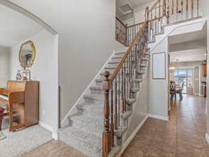 Stairs featuring arched walkways, tile patterned floors, a high ceiling, a chandelier, and carpet floors