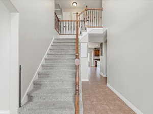 Stairway featuring a towering ceiling and tile patterned flooring