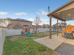 Fenced backyard with a playground, a patio, and a residential view