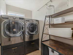 Laundry area with independent washer and dryer and light tile patterned floors