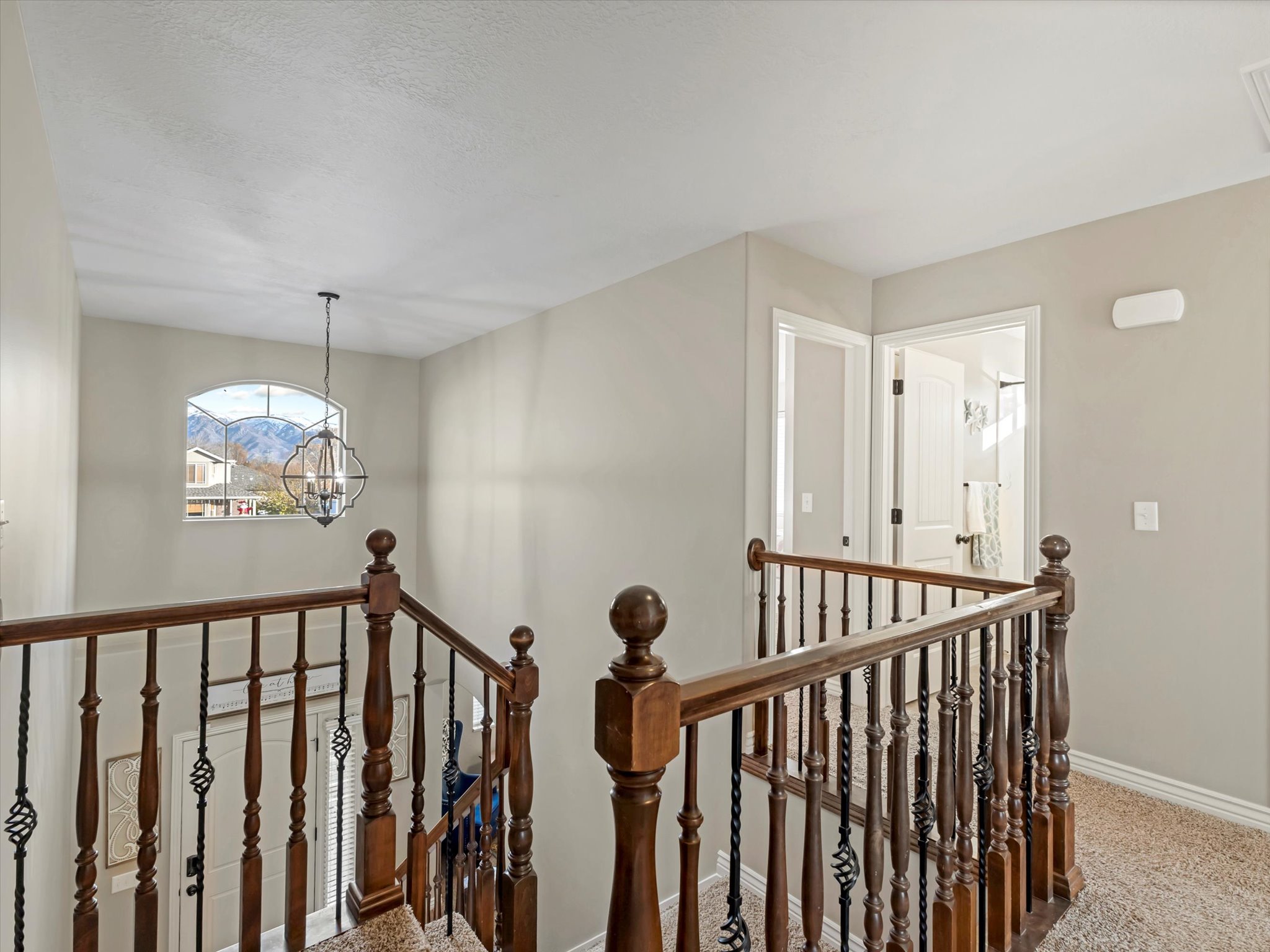 Corridor featuring an upstairs landing, a chandelier, and carpet
