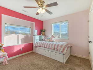 Carpeted bedroom with ceiling fan and multiple windows