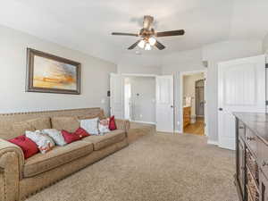 Living room featuring light colored carpet, ceiling fan, and lofted ceiling