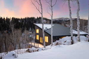 View of front facade with a deck, a metal roof, and a forest view