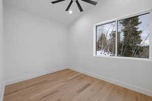 Spare room featuring vaulted ceiling, light wood-style floors, and recessed lighting