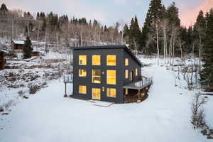 Snow covered back of property with a deck