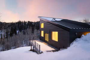 View of snow covered exterior featuring a deck and a metal roof