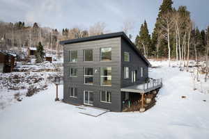 Snow covered rear of property with a wooden deck