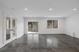 Empty room with concrete floors, french doors, recessed lighting, and plenty of natural light