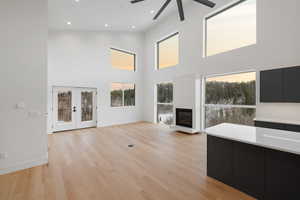 Unfurnished living room with french doors, light wood finished floors, recessed lighting, a glass covered fireplace, and a ceiling fan