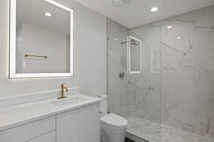 Bathroom with vanity, a marble finish shower, and recessed lighting