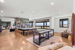 Recreation room featuring finished concrete floors, healthy amount of natural light, and recessed lighting