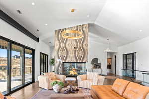 Living room with a fireplace, wood finished floors, high vaulted ceiling, and recessed lighting