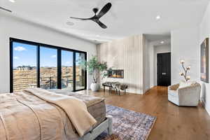 Bedroom featuring access to outside, wood finished floors, recessed lighting, a fireplace, and a ceiling fan