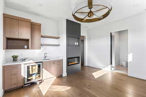 Kitchen featuring open shelves, beverage cooler, dark wood-style floors, light stone countertops, and ceiling fan