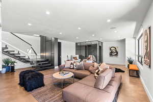 Living room featuring concrete floors, stairs, and recessed lighting