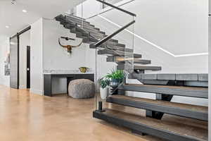 Stairs featuring a barn door, recessed lighting, and finished concrete flooring