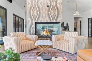 Living area with a high end fireplace, lofted ceiling, a chandelier.