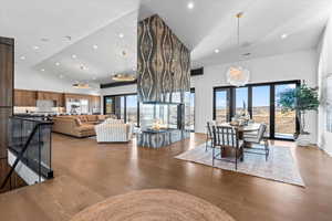 Dining room with wood finished floors, recessed lighting, a multi sided fireplace, a chandelier, and a towering ceiling