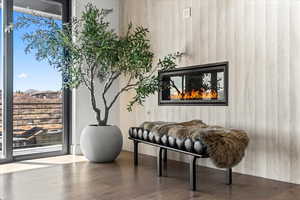 Sitting room with wooden walls, wood finished floors, and a glass covered fireplace