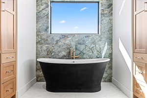 Full bath with tile walls, a soaking tub, and an accent wall