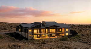 Rear view of property featuring, stone siding, a metal roof, and a chimney