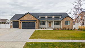 View of front of home featuring a porch, a standing seam roof, driveway, an attached garage, and brick siding