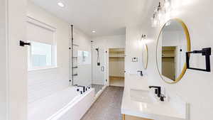 Full bath with a spacious closet, a garden tub, double vanity, a stall shower, and light tile patterned floors